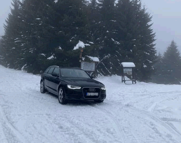 Zaparkované auto v zasněžené krajině.